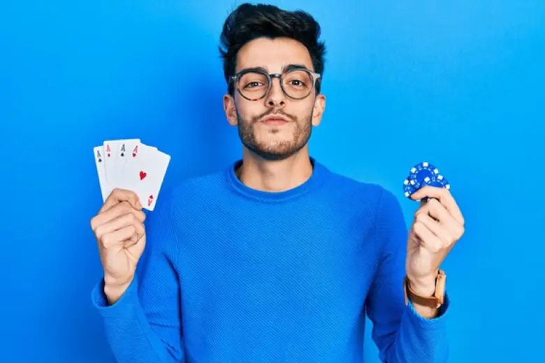 A man wearing glasses is displaying two cards and a playing card in his hand and earning money 
