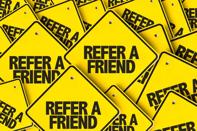 A stack of yellow signs saying Refer a Friend with the additional information Get Paid for Sharing links