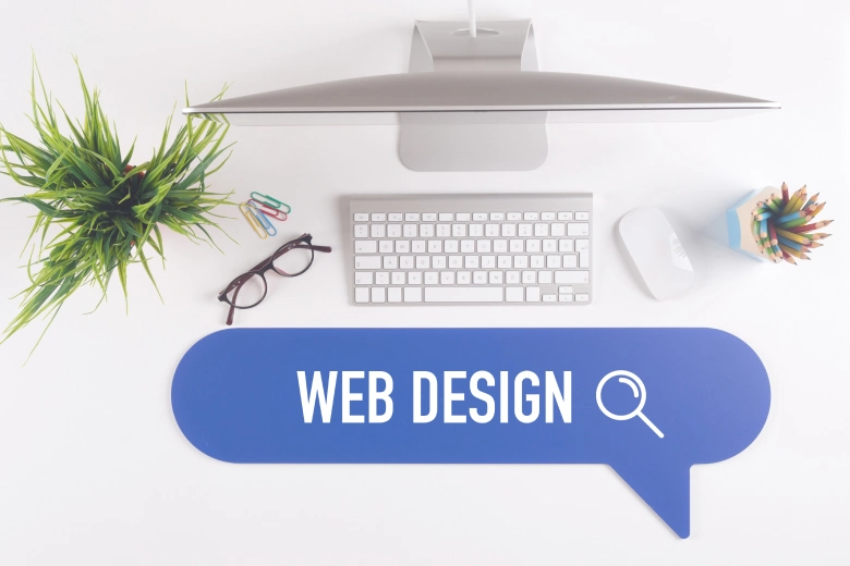 A desk with a keyboard, mouse, plant and a magnifying glass shows a Web Design 